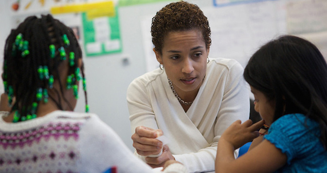 African American female teacher working with young hispanic female student showing understanding and care