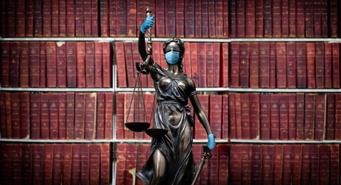 Lady liberty wearing a pandemic mask standing in front of shelves of legal books