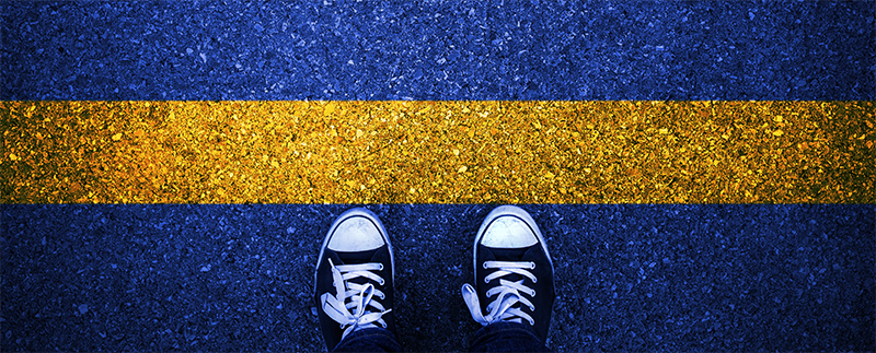 young person's feet in sneakers at a yellow asphalt starting line