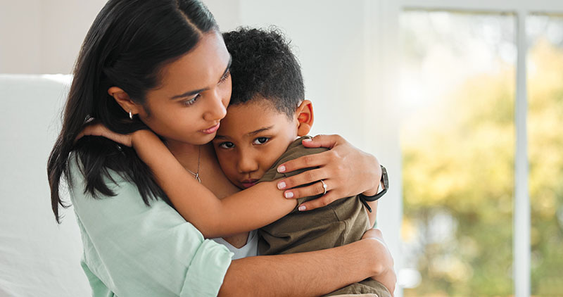 Young Hispanic mother holding her son, worried, at home