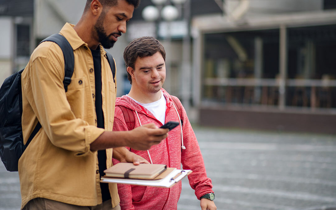 A young man with disabilities learning how to navigate with his cell smartphone with his CBI instructor