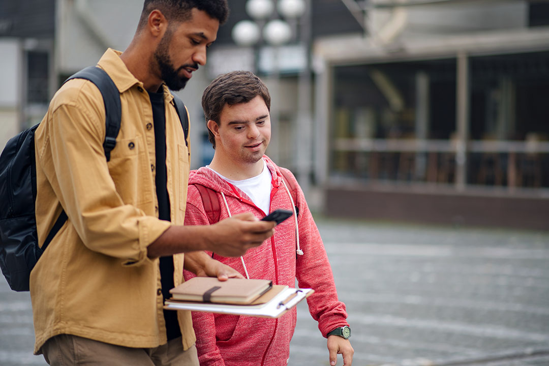 Portrait Of School Pupils Playing On Climbing Frame A young man with disabilities learning how to navigate with his cell smartphone with his CBI instructor