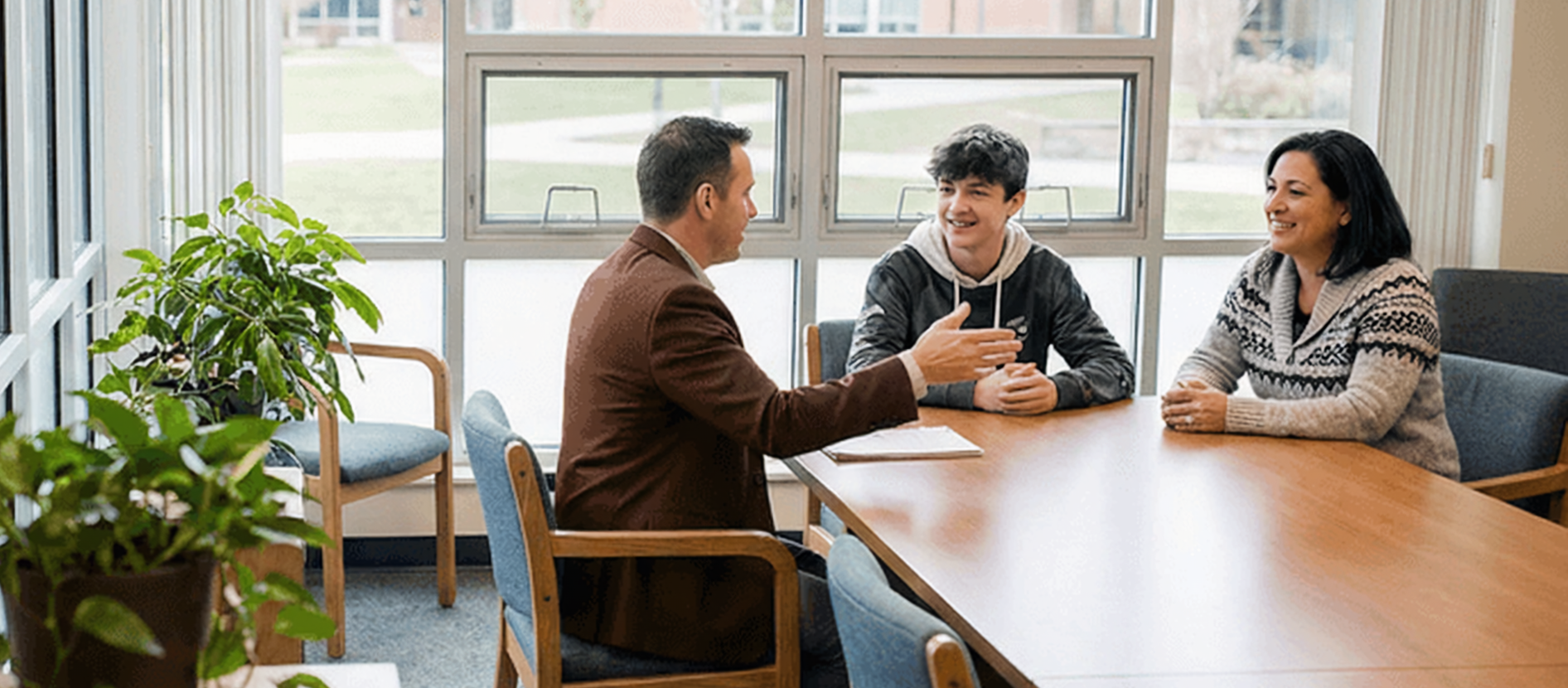 Portrait Of School Pupils Playing On Climbing Frame Male social worker working with a teen male student and his mother in a sunny school conference room.